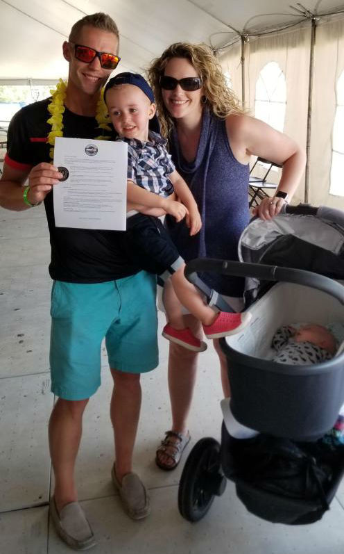 Brown, his sons Aidan and Ethan (sleeping), and his wife Gill pose with the Kona Ironman contract. (Submitted)