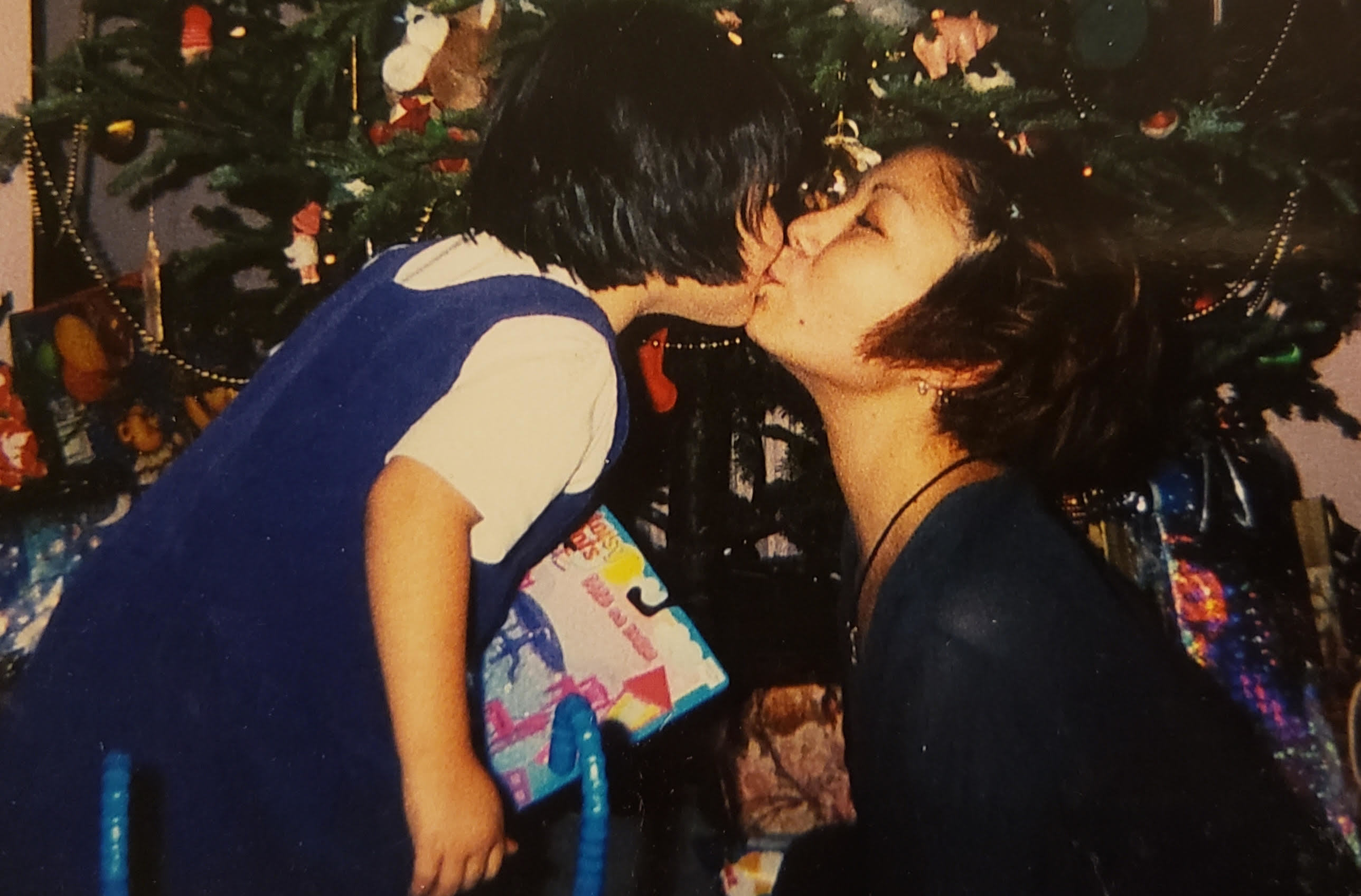 Mary Evans Harlick gives her young daughter, Amena, a kiss under the Christmas tree. (Submitted by Amena Evans Harlick)