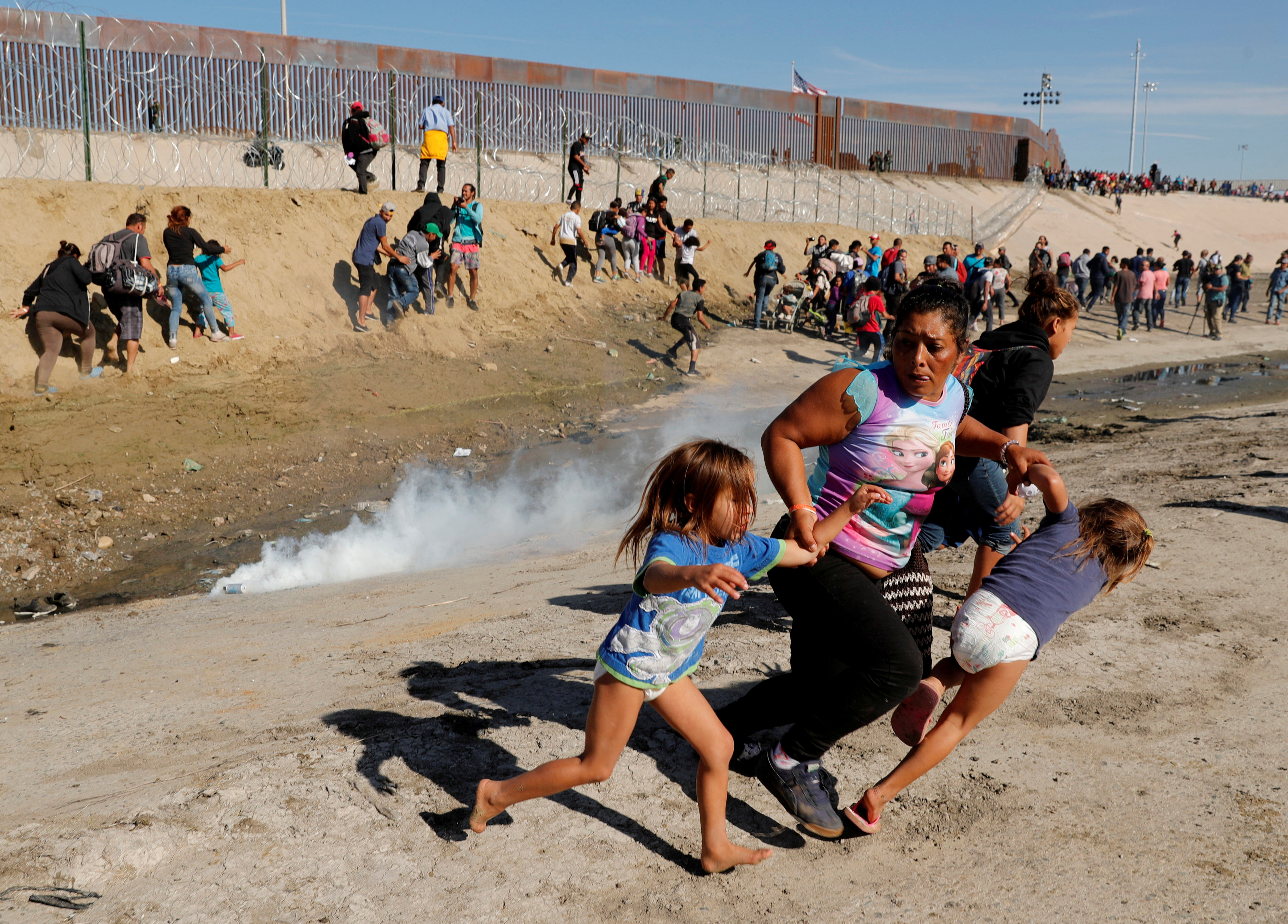 On Oct. 13, between 5,000 and 7,000 Hondurans and other Central Americans started walking toward the United States, hoping for asylum. They reached the U.S.-Mexico border in mid-November. In this photo, María Lila Meza Castro, a 39-year-old migrant woman from Honduras, runs from tear gas with her twin daughters in front of the border wall between the U.S. and Mexico. (Kim Kyung-Hoon/Reuters)