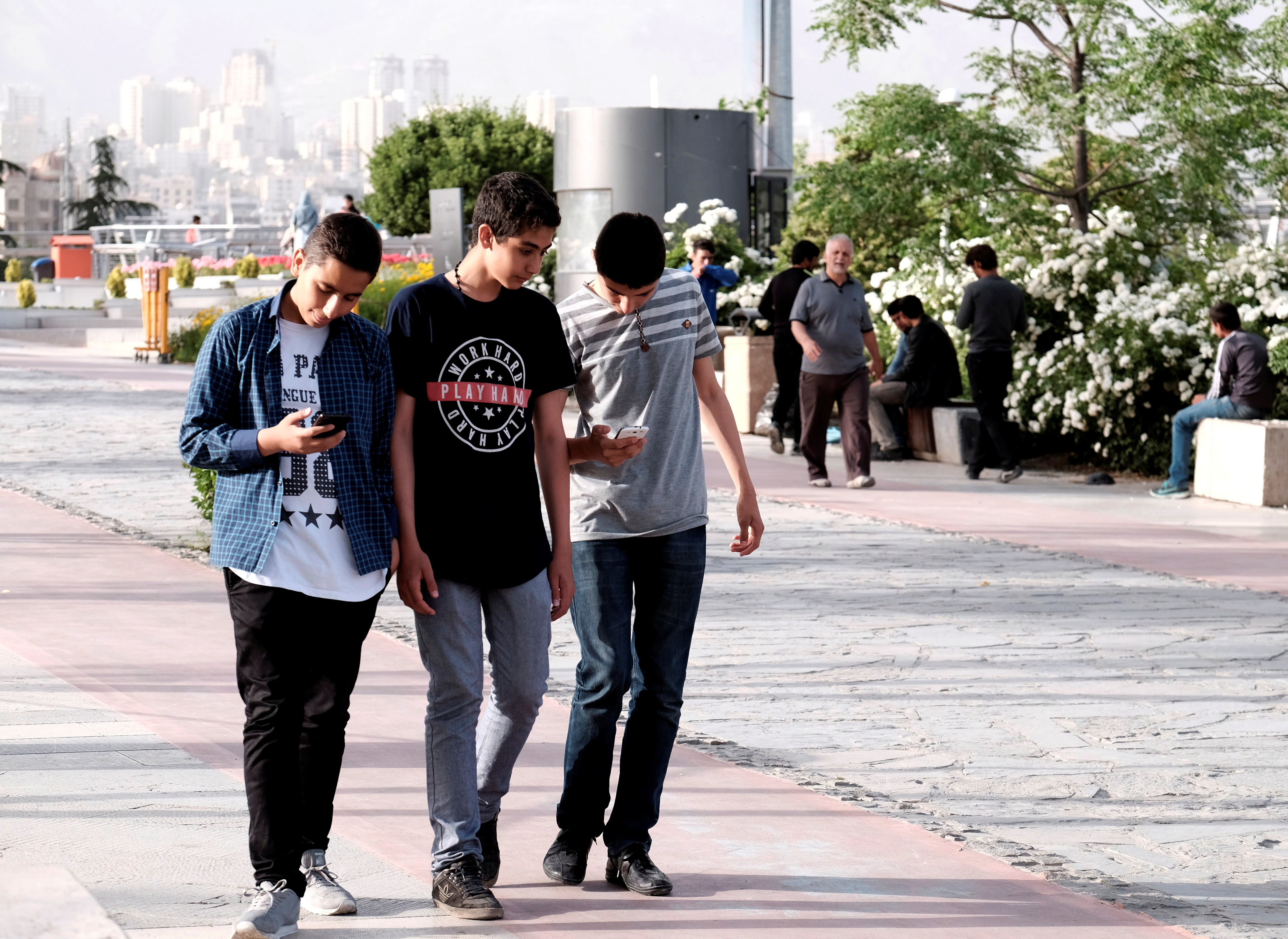 Iranian youth use their mobile phones as they walk at a park in Tehran on May 16, 2017. (Reuters/TIMA)