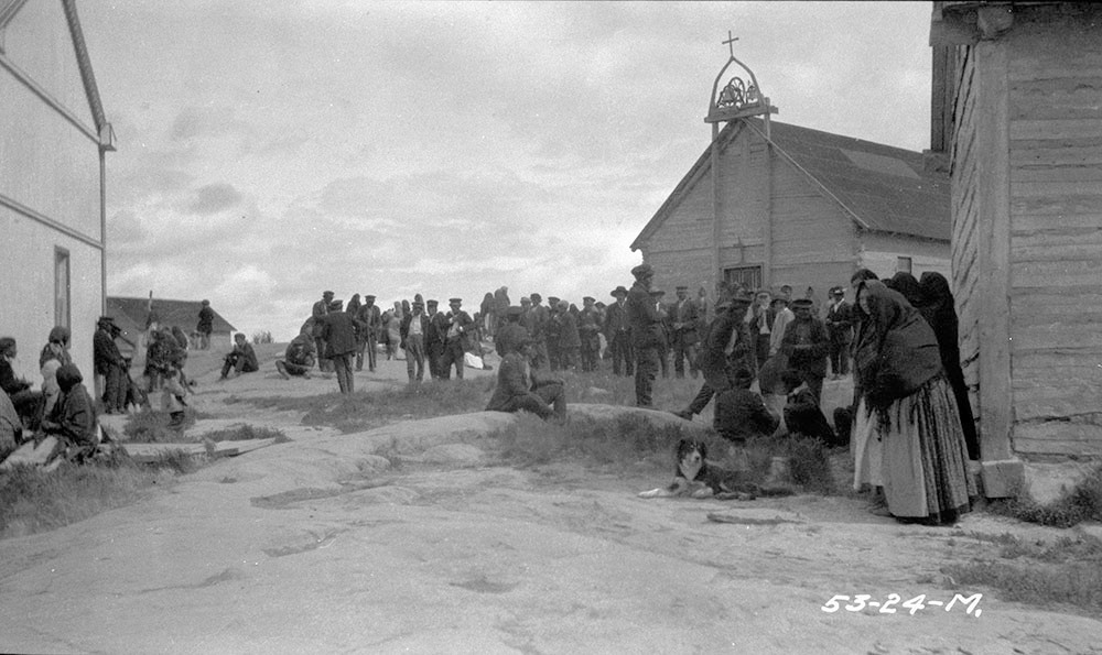 The community at Fort Rae gathering in front of the Roman Catholic mission church in 1924. Treaty documents were in several places entrusted to local priests, who lost or destroyed them during epidemics. (J. F. Moran / Department of Indian Affairs and Northern Development fonds / Library and Archives Canada / a102611-v8)