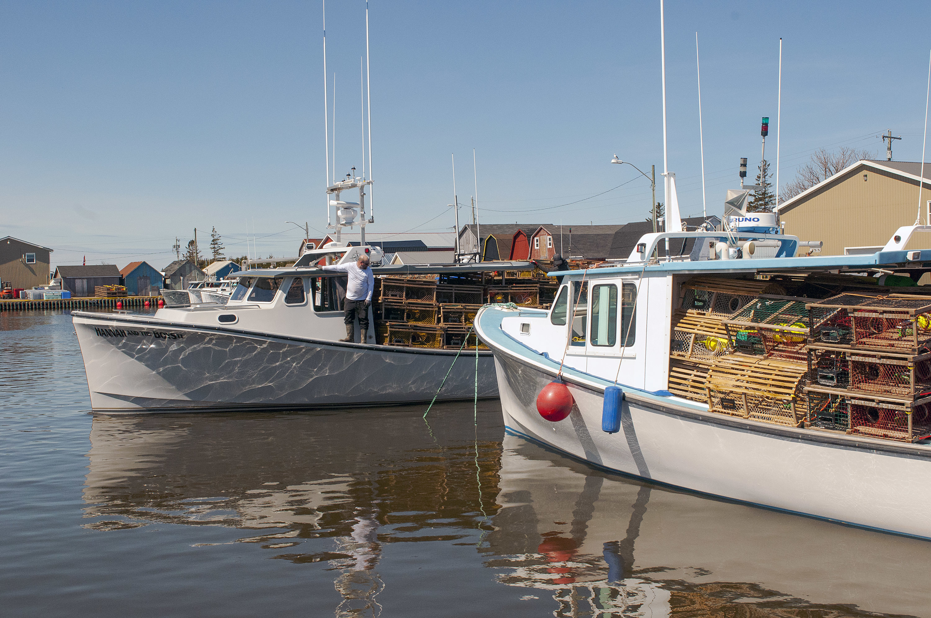 One fully laden with its second load of traps, a lobster boat leaves the Malpeque Harbour wharf as another boat is still being loaded with the second set. (Brian McInnis/CBC)