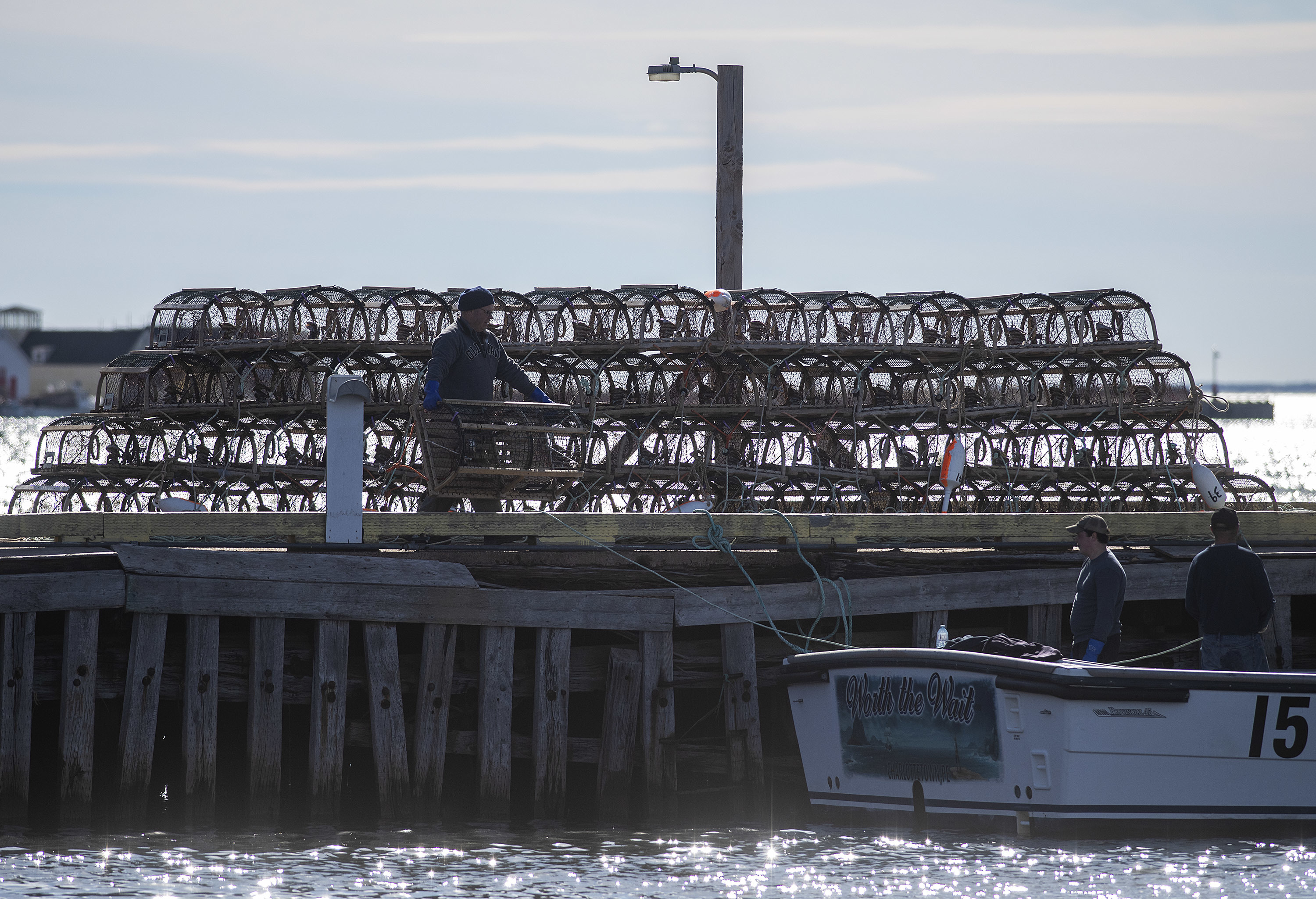 Traps are silhouetted on the wharf as fishermen bait them and load them onto a boat. (Brian McInnis)