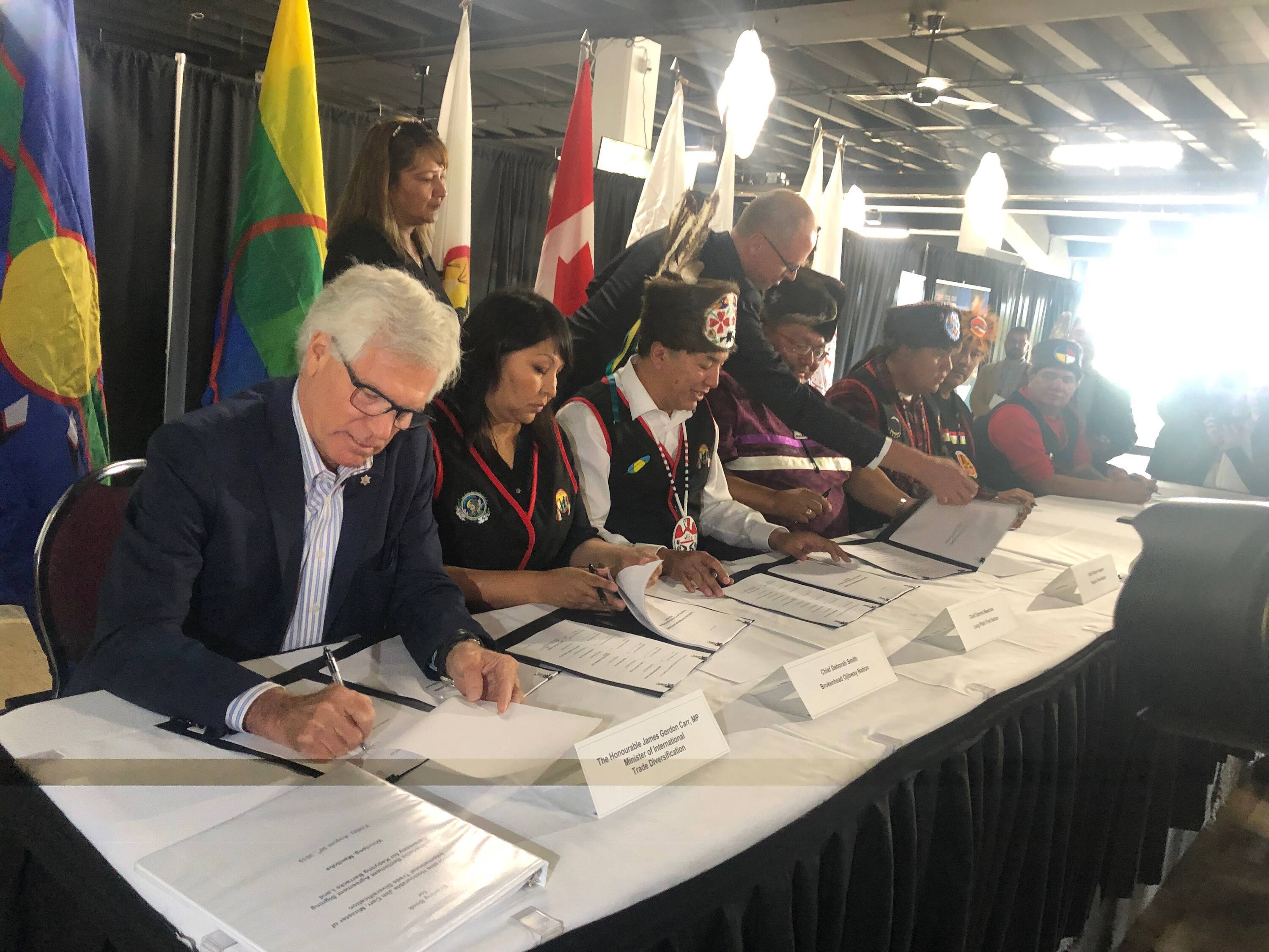 MP Jim Carr, left, and the heads of seven First Nations sign an official agreement for Kapyong Barracks in 2019. (Sean Kavanagh/CBC)