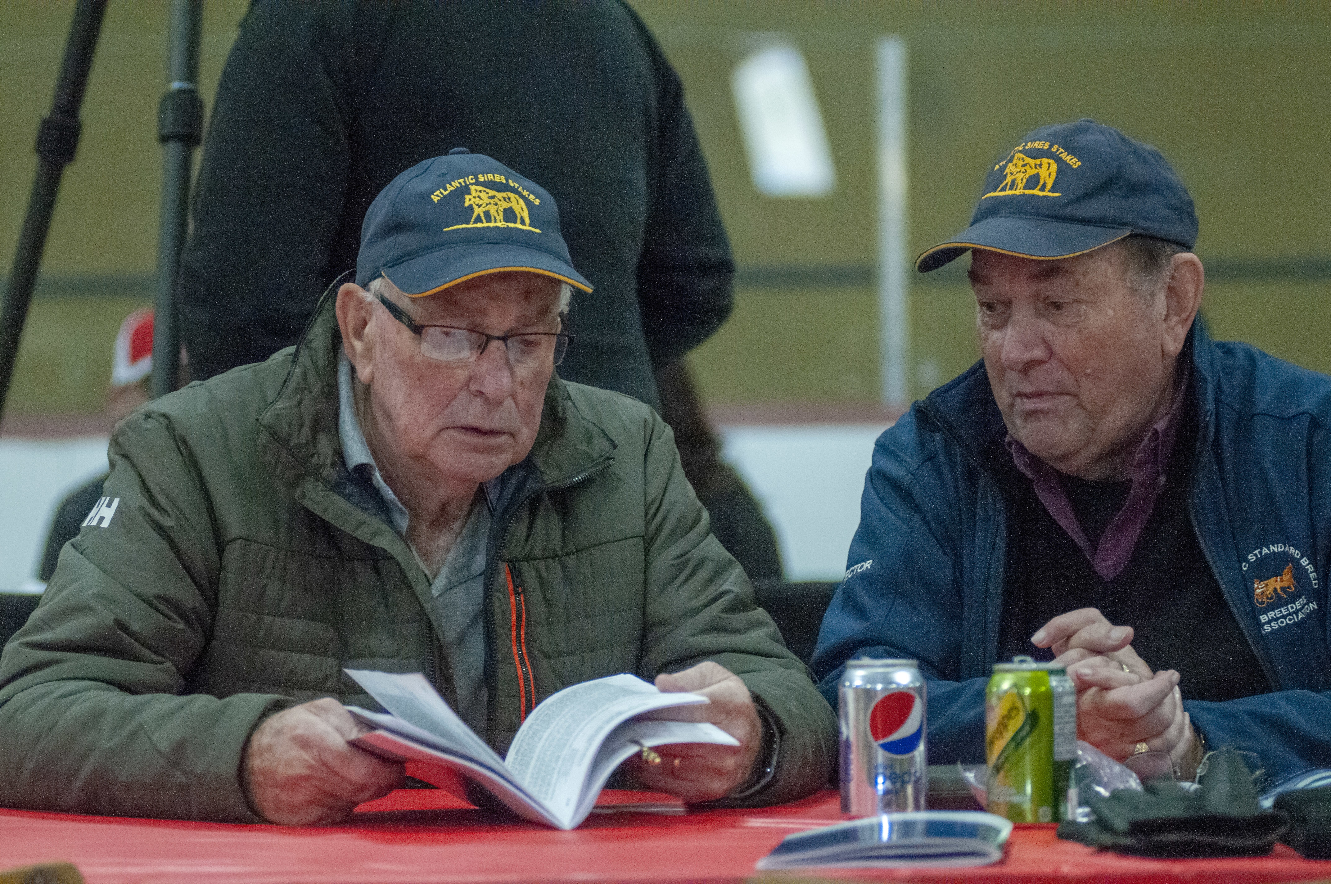 Daniel Ross, left, of Belfast and Wayne MacRae of Fall River, N.S., examine the program with the names and backgrounds of the horses that will be sold. They are both horse owners. (Brian McInnis/CBC)