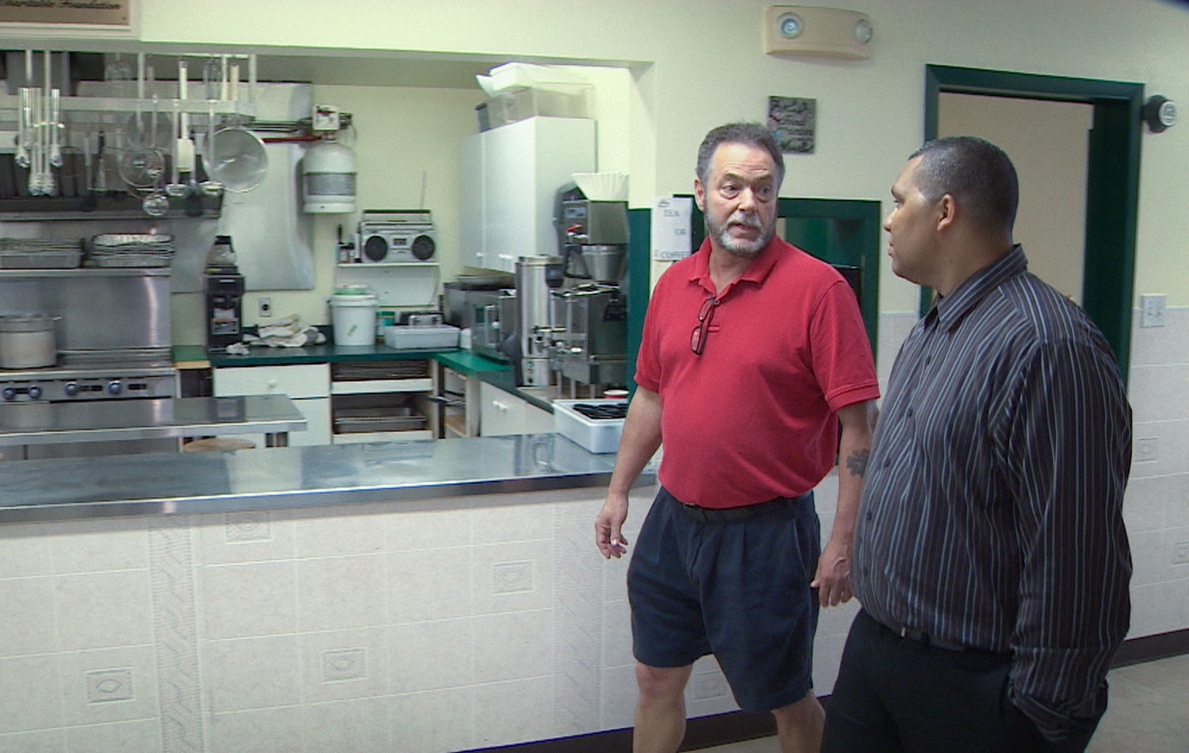 Hope Cottage executive director Joe Morgan, left, walks with Arsenault past the charity's kitchen. (Robert Short/CBC)