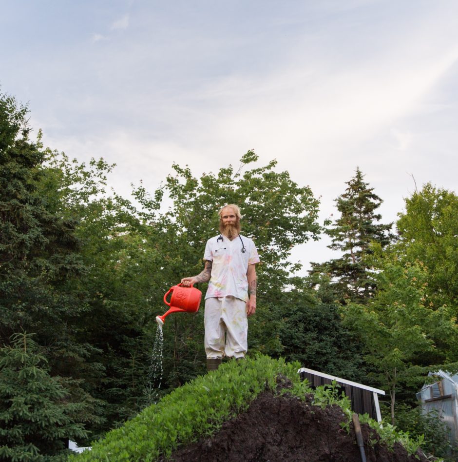 Jamie Tingley of Off Beet Farm pours water from a watering can while wearing his old nursing outfit.