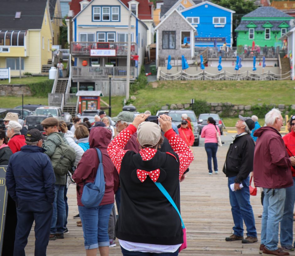 A tourist on a wharf in Lunenburg, N.S., snaps a photo of the historic town.