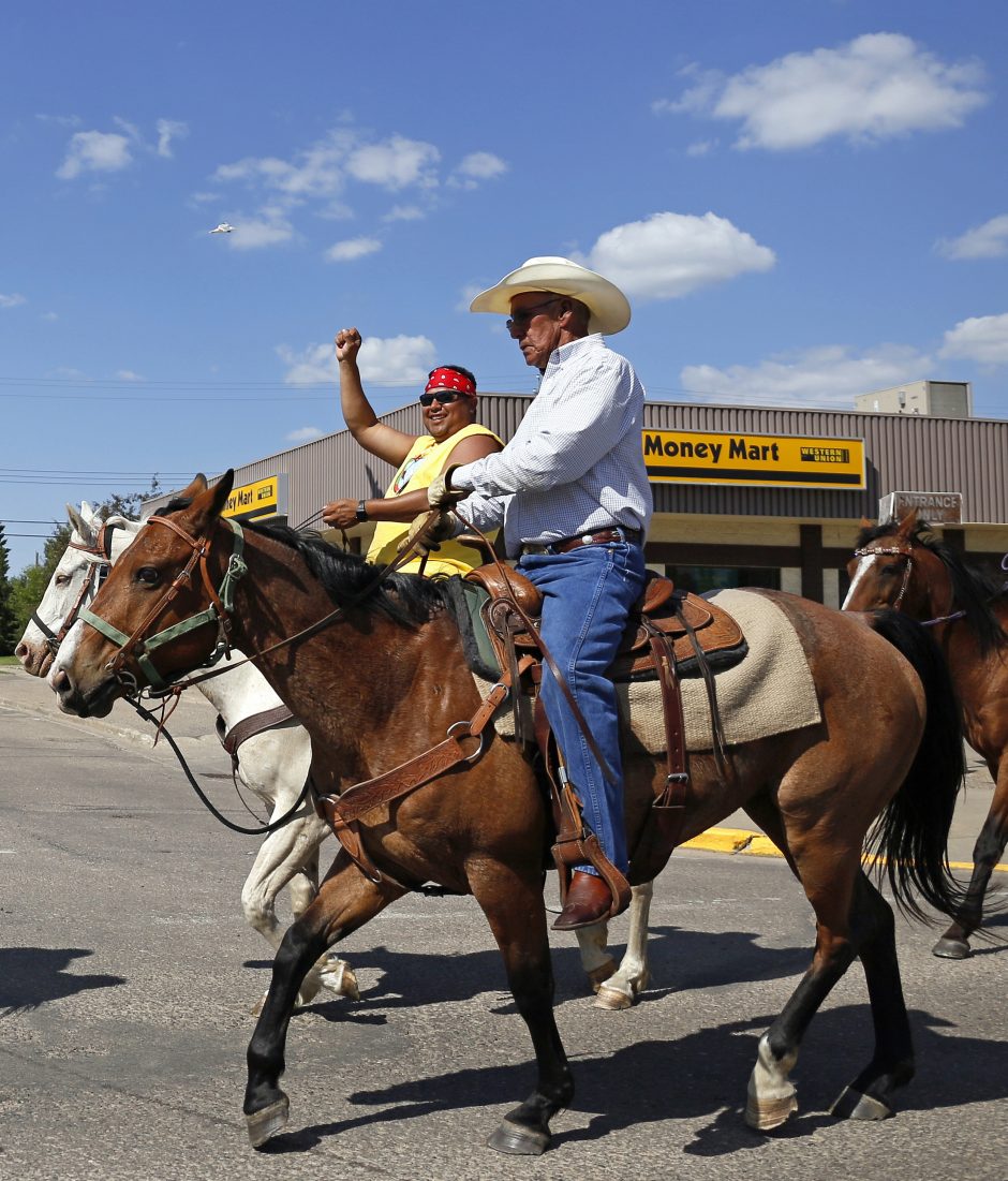 Ben Badger, with his fist in the air, and the rest of the riders going through St. Paul on horses.