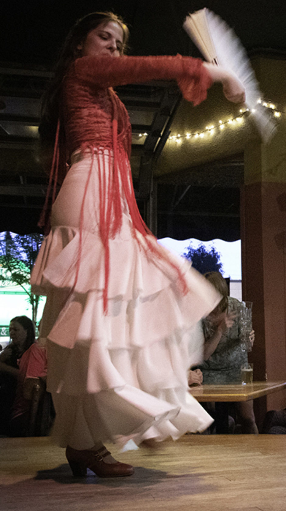 A flamenco dancer holds a fan on stage.