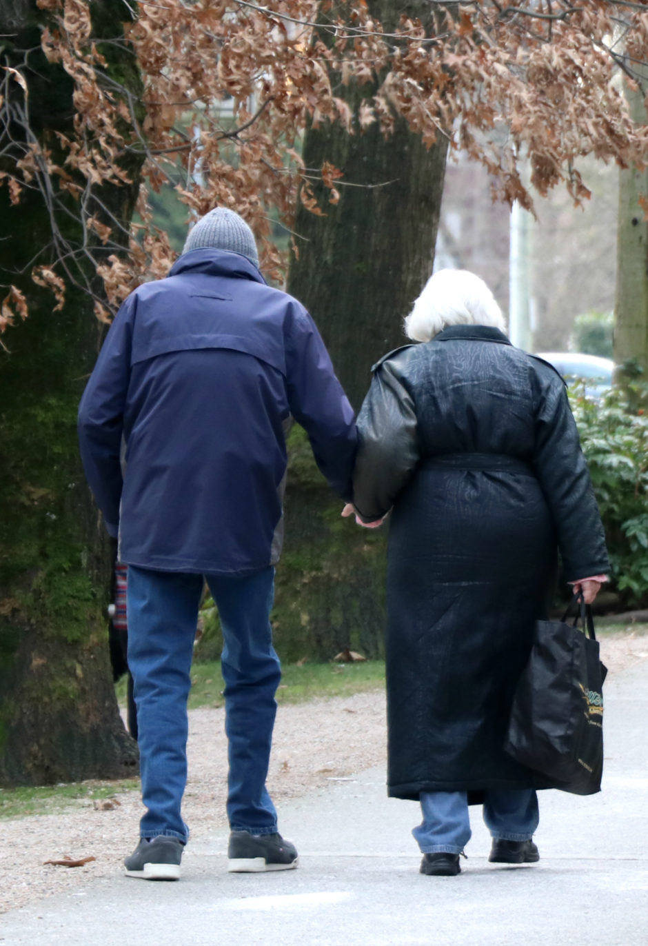 An older couple walks down a tree-lined street in Vancouver