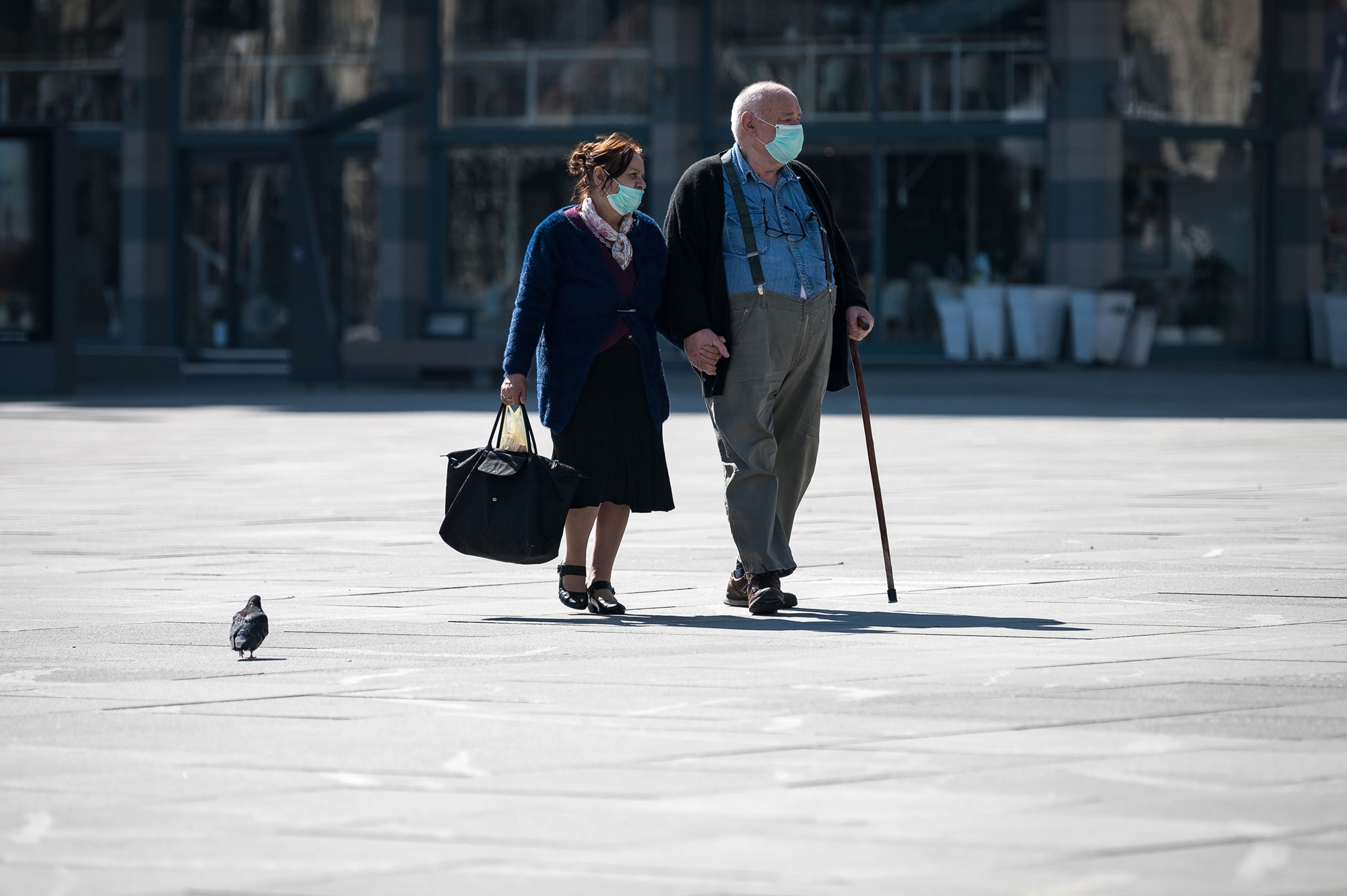 An elderly couple wearing protective masks walks through Belgrade's main square on March 17, after Serbia's president said the new restrictions were necessary to 'save our elderly.' (Andrej Isakovic/AFP via Getty Images)