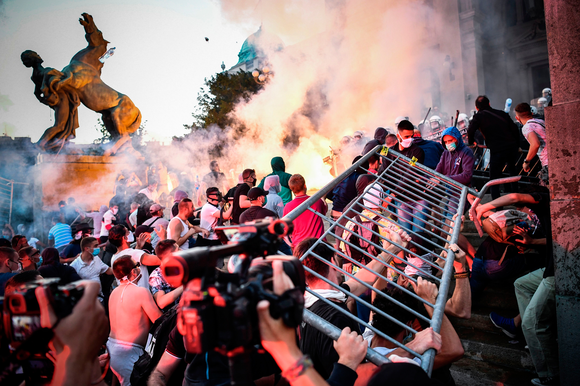 Protesters clash with police in front of Serbia's National Assembly building in Belgrade on July 8 during a demonstration against a weekend curfew announced to combat a resurgence of COVID-19 infections. (Andrej Isakovic/AFP via Getty Images)