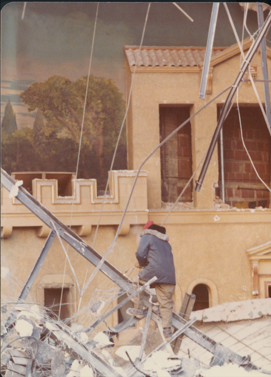 A worker dwarfed by the painted scenery dismantles the theatre. (Saskatoon Public Library; item PH-2006-13-6)