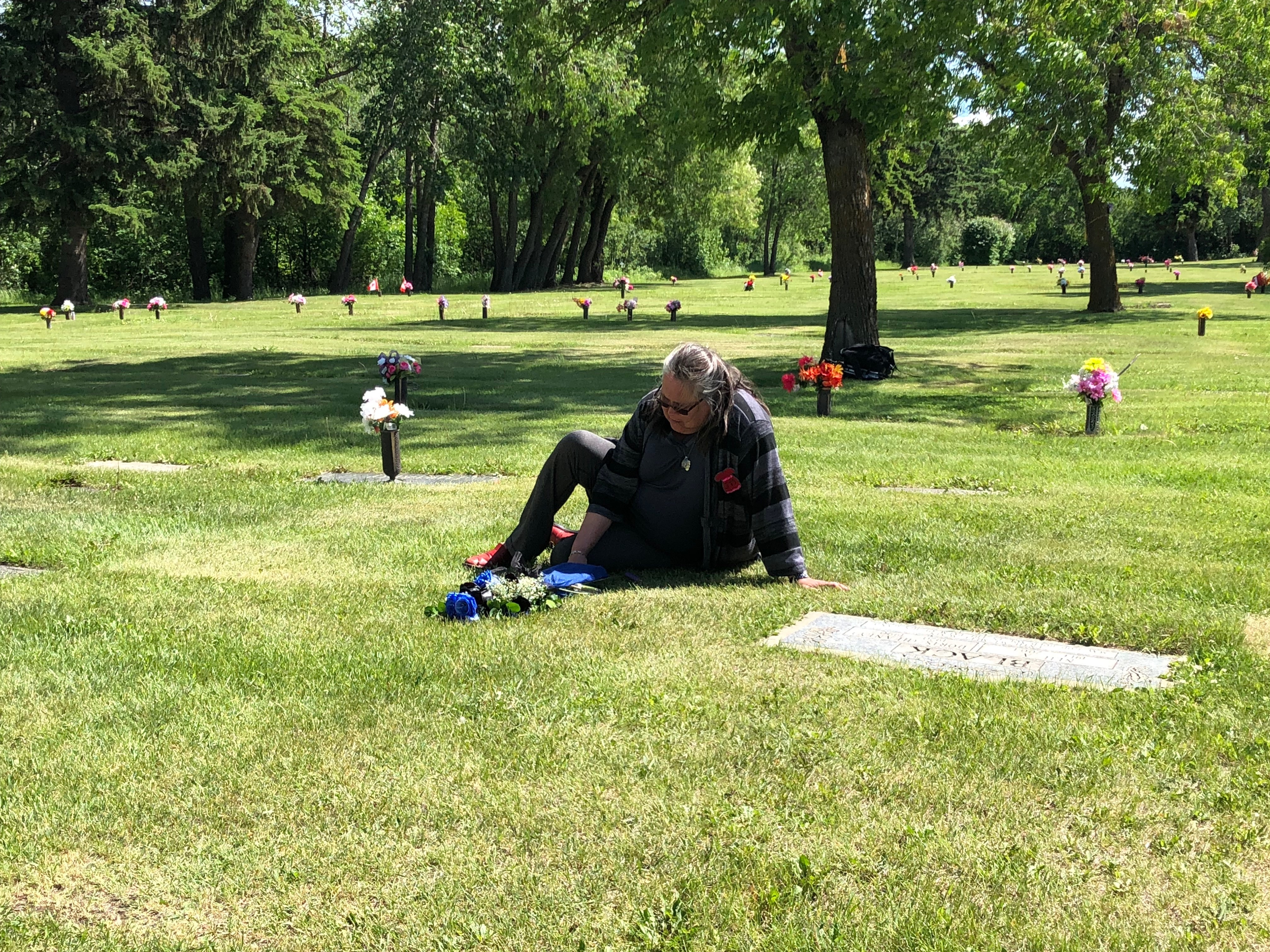 Bird brought a dozen roses to the cemetery, dyed blue and black, Mercredi’s favourite colours. (Rachel Zelniker/CBC)