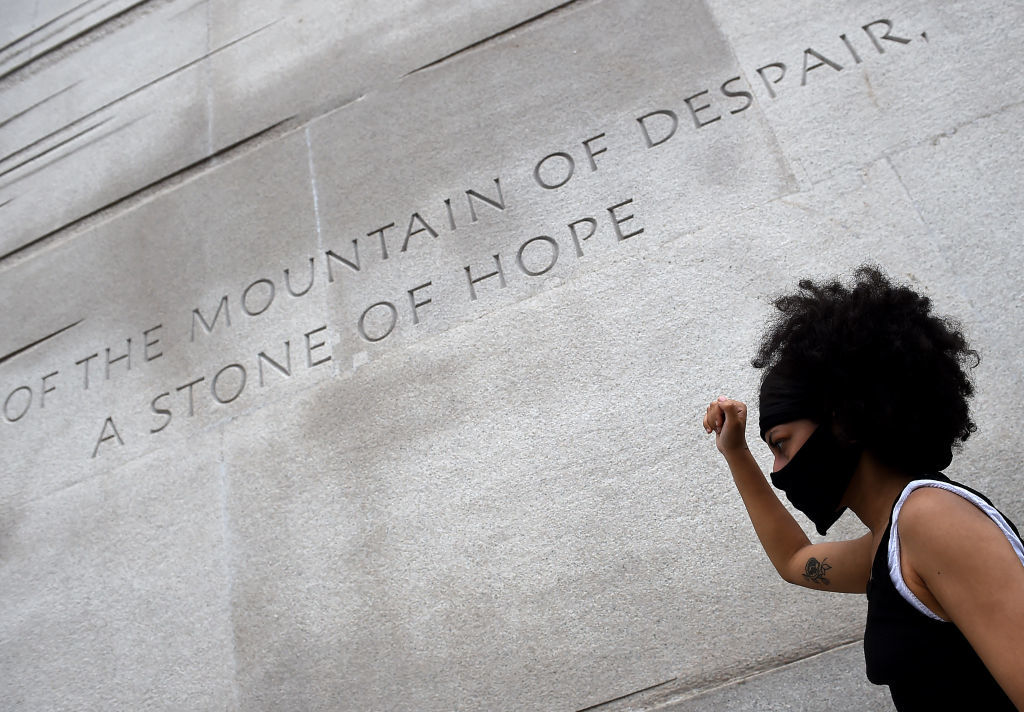 A woman walks past part of the Martin Luther King Jr. Memorial on the National Mall in D.C. during the Juneteenth protest. The memorial includes a massive statue of King inscribed on the side with a quote from his famous 1963 speech, I Have a Dream: 'Out of the mountain of despair, a stone of hope.' (Olivier Douliery/AFP/Getty Images)