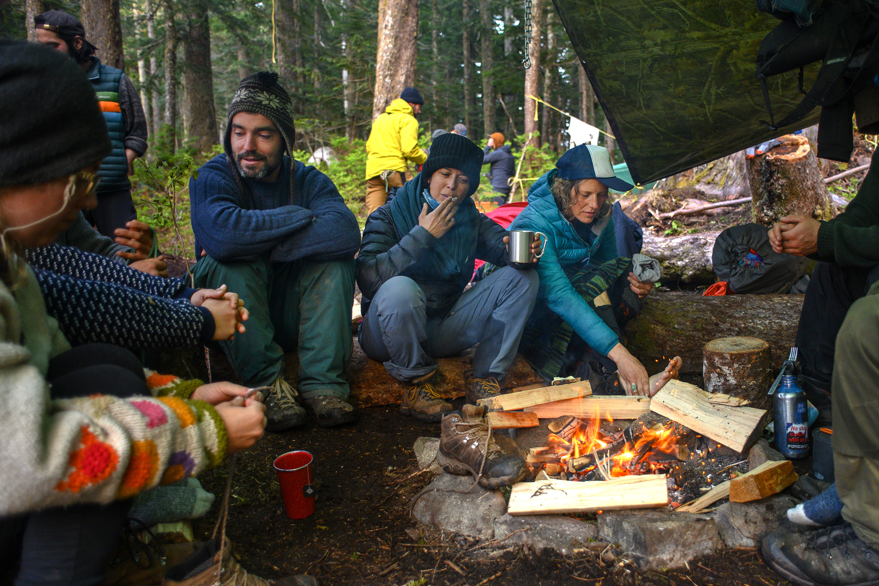 Activists at a protest site known as Ridge Camp near the headwaters of Fairy Creek on southwestern Vancouver Island rest and warm their feet by the fire. Some have been in the camp for months. (Kieran Oudshoorn/CBC)