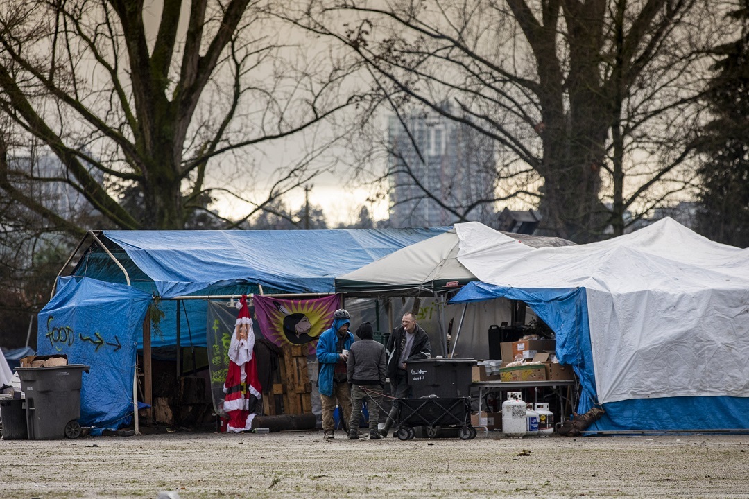 People gather around a makeshift kitchen at the park in December where donated food is available to campers. (Ben Nelms)