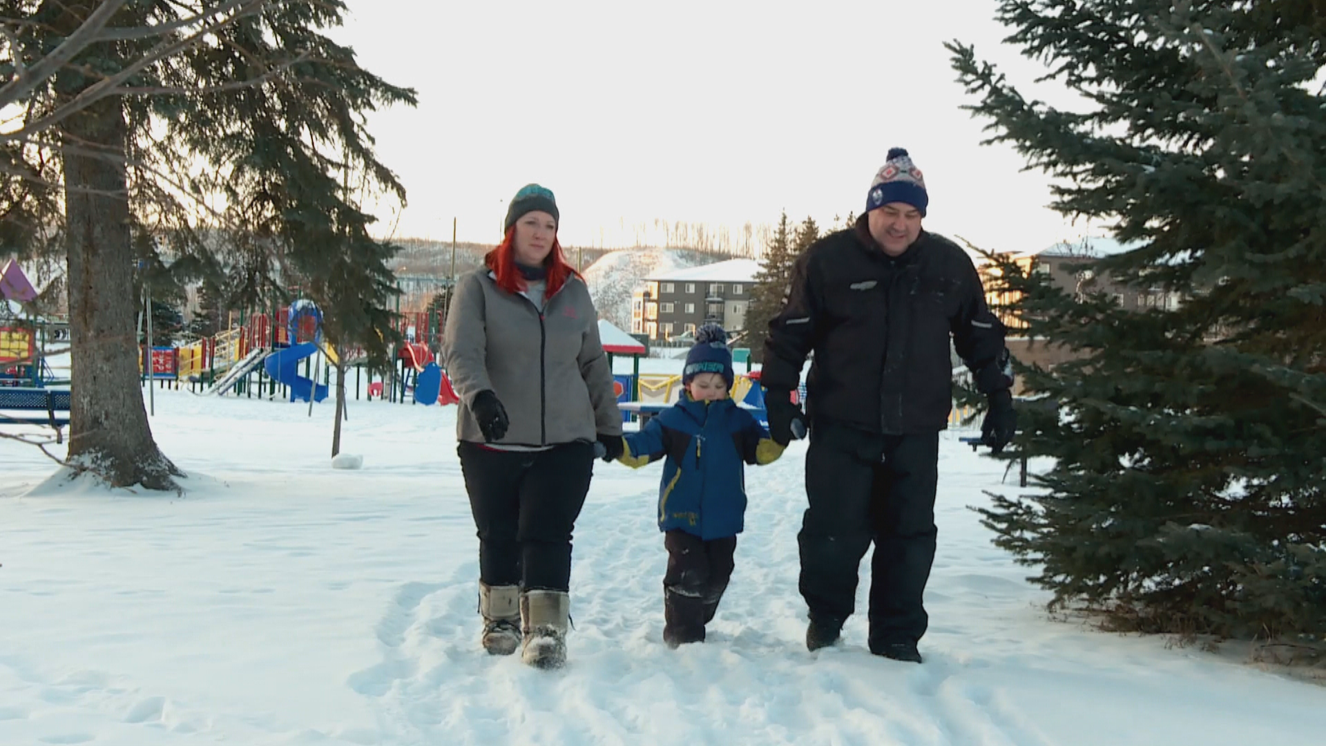 Jennifer Hamel (left) and Peter Hamel (right) walk with their four-year-old son, Jamie (middle), at a playground in Fort McMurray. (Jamie Malbeuf/CBC)