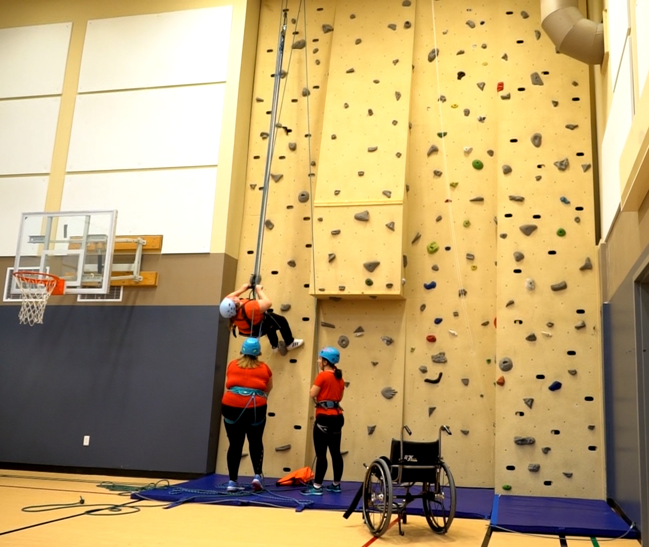 Hayley Redmond, centre, participates in wall climbing, with the help of some spotters, at the Easter Seals gym in St. John's. (Sherry Vivian/CBC)