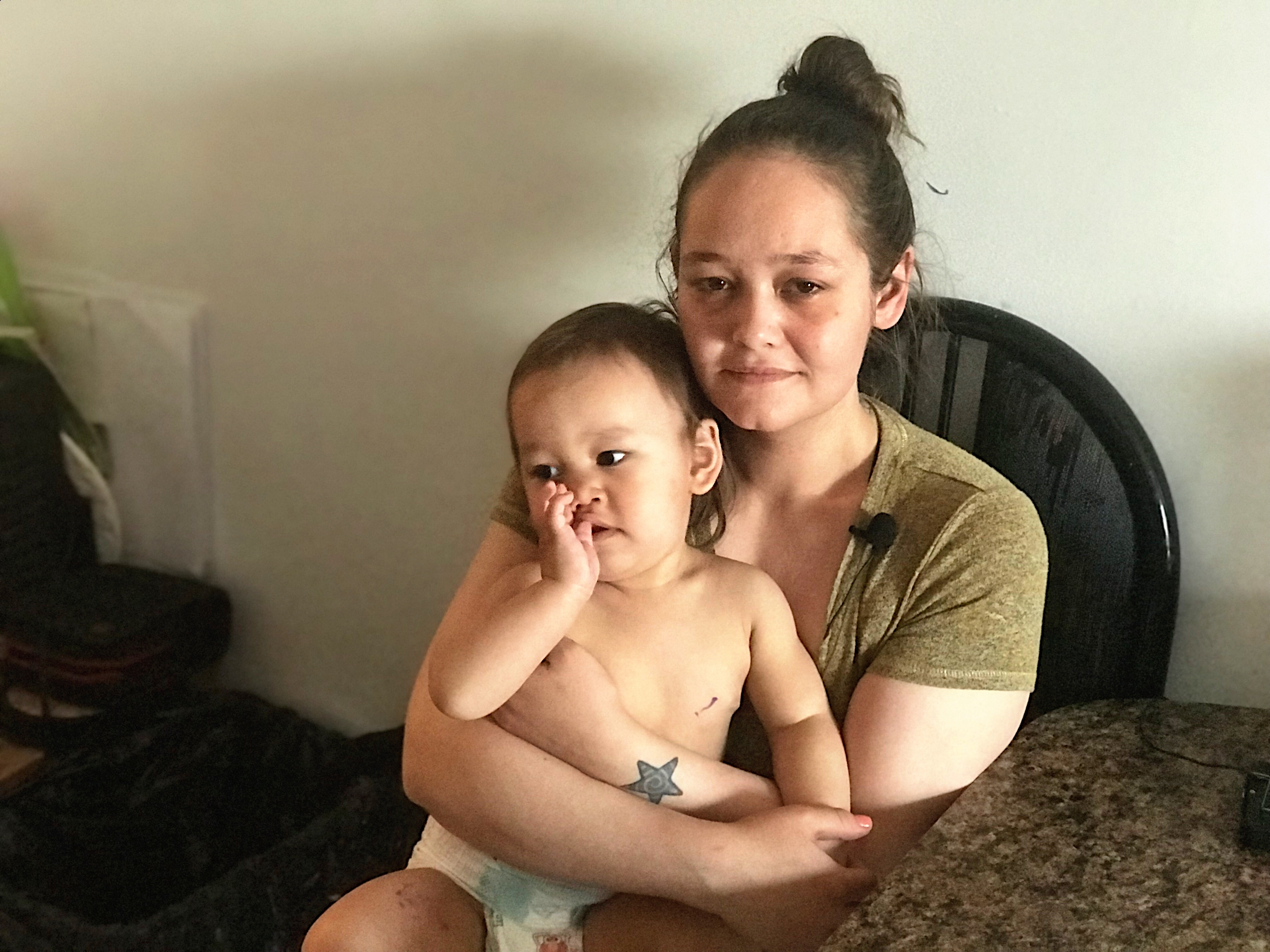 Twenty-nine year-old Megan Klengenberg holds her young son Jacksyn in her home in Kugluktuk. She is now a single mother of three children. (Hilary Bird/CBC)