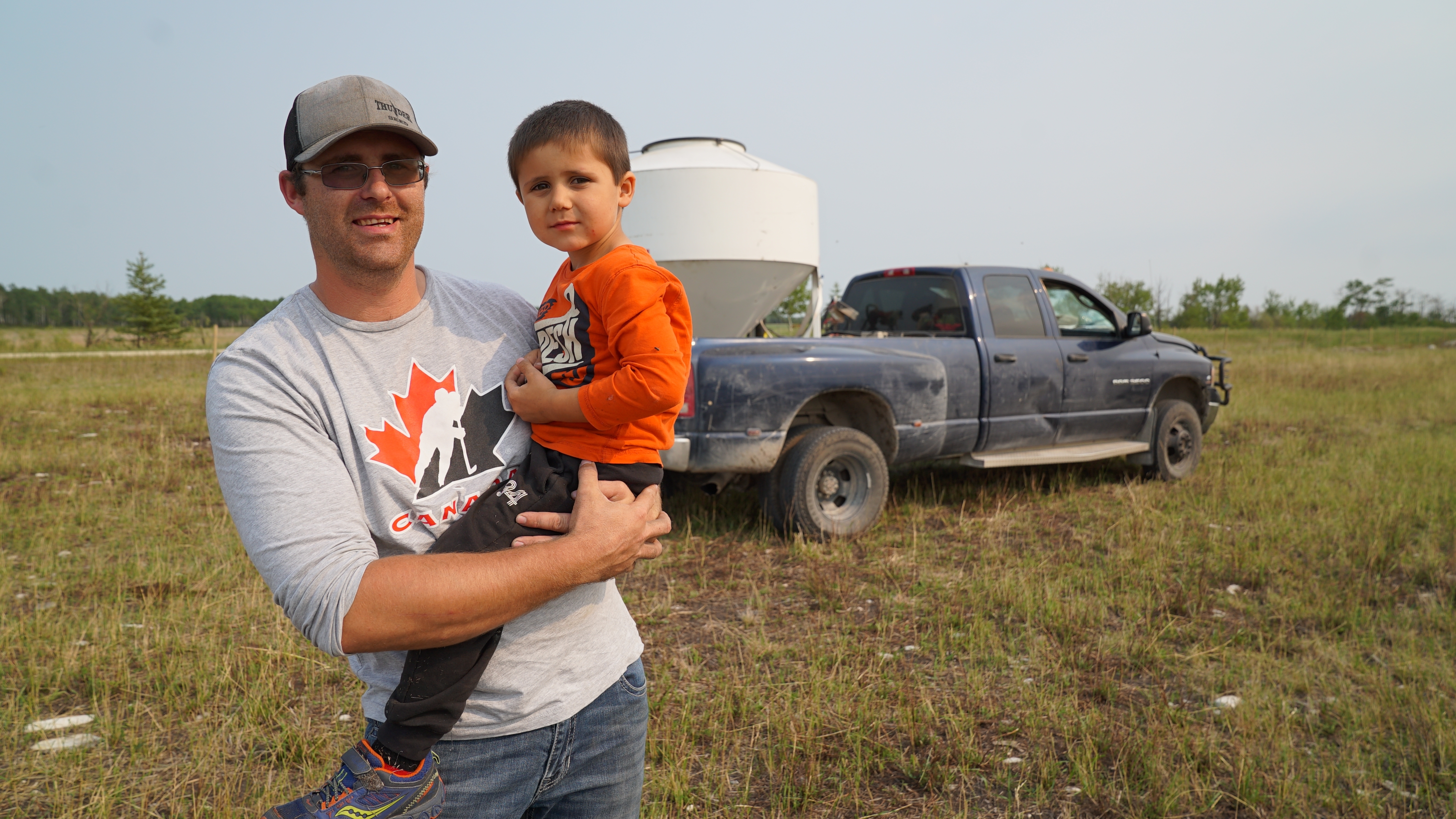 Rancher and auction manager Kirk Kiesman with his son Asher, 4. 'There’s people crying in the stands when their animals sell,' Kiesman says. 'There’s people that are upset.' (Jaison Empson/CBC)