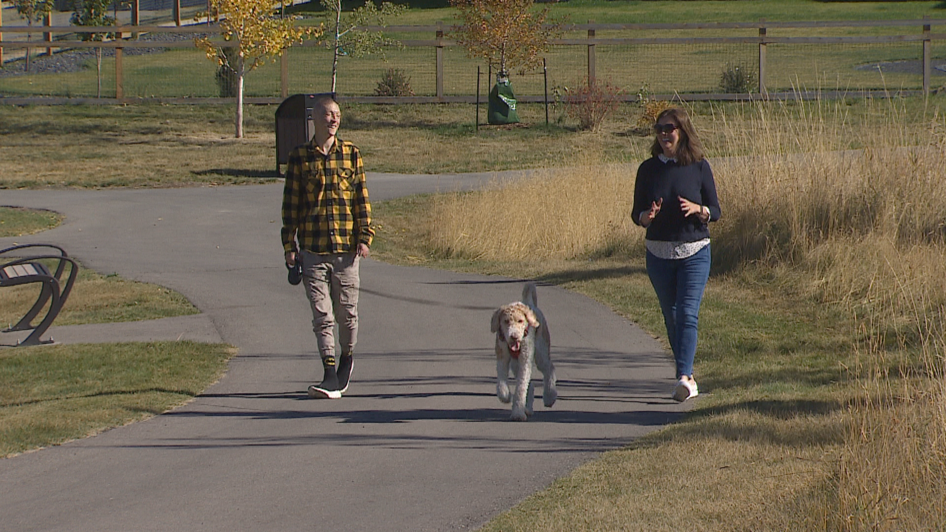 Kyle Hynes (left) walks with his dog, Simba, and his friend, Colette Williams (right), on a trail near his home in Springbank, Alta. (Justin Pennell/CBC)