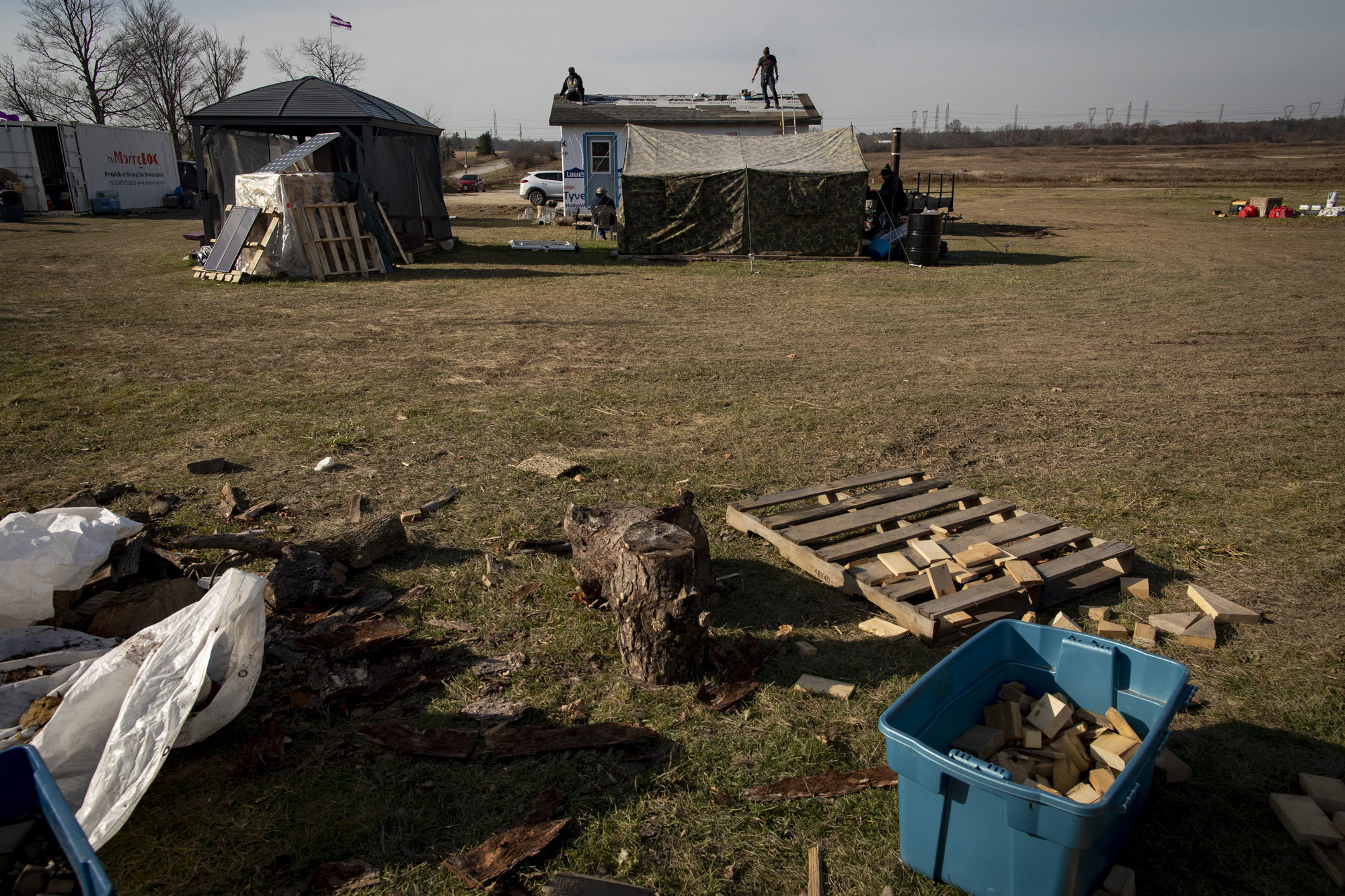 Six Nations members lay shingles on a structure in the Kanonhstaton camp. (Evan Mitsui/CBC)