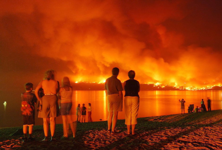 On Aug. 21, 2003, People gather at Marina Park near Kelowna, B.C. to watch flames across Lake Okanagan creeping closer to Mission area homes.