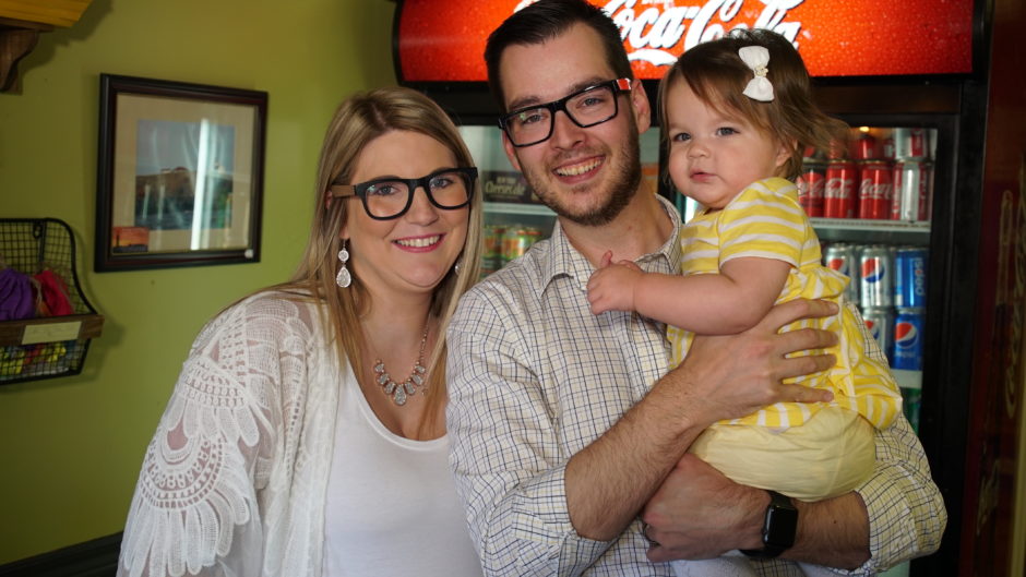 Nanci and Colin Corcoran hold their daughter Nora behind the counter of their restaurant the Celtic Knot Pub & Restaurant, in St. Mary's. (Mark Cumby/CBC)