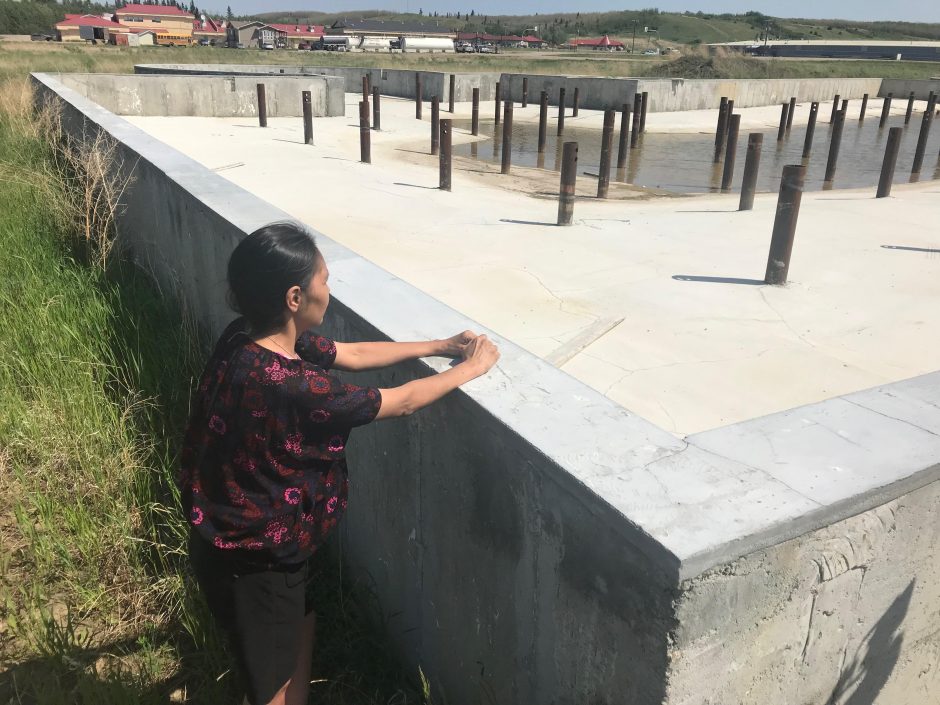 Charmaine Stick, a woman from Onion Lake Cree Nation, stands looking at the unfinished embassy project.