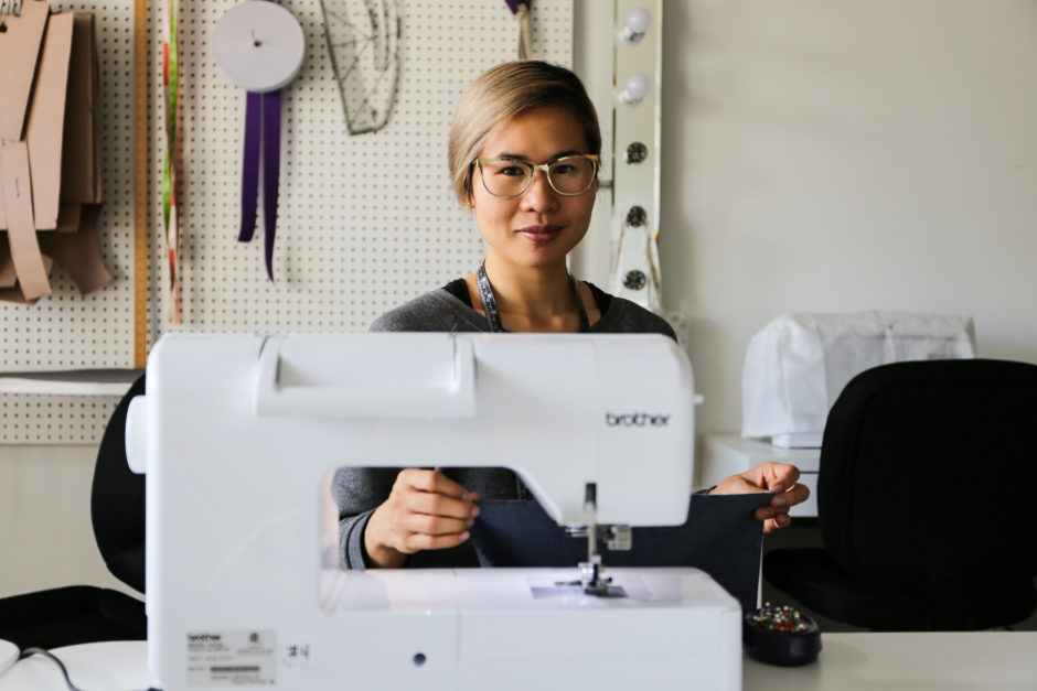 Beverly Gan sitting behind a sewing machine. 