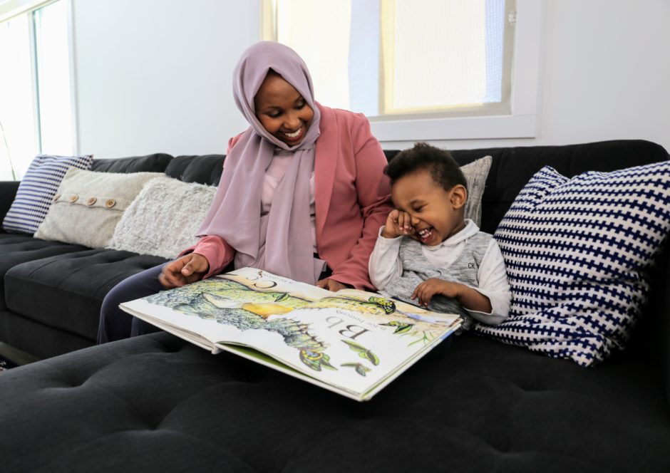 Sucdi Barre reads to her son Yonis as he laughs.