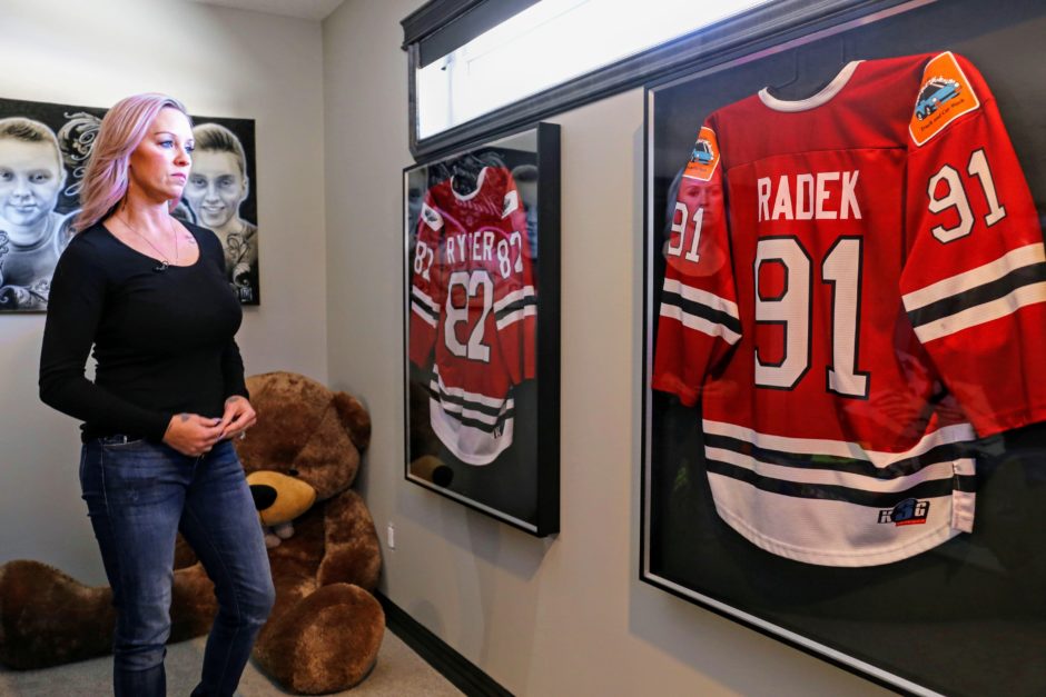 Tracy Stark looks at framed jerseys bearing her sons' names.