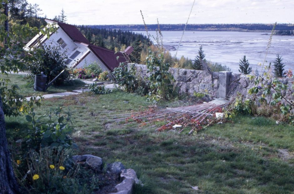 After the landslide, shifting sand carried two houses over the high riverbank and left a third teetering over the edge. (Northern Life Museum & Cultural Centre)