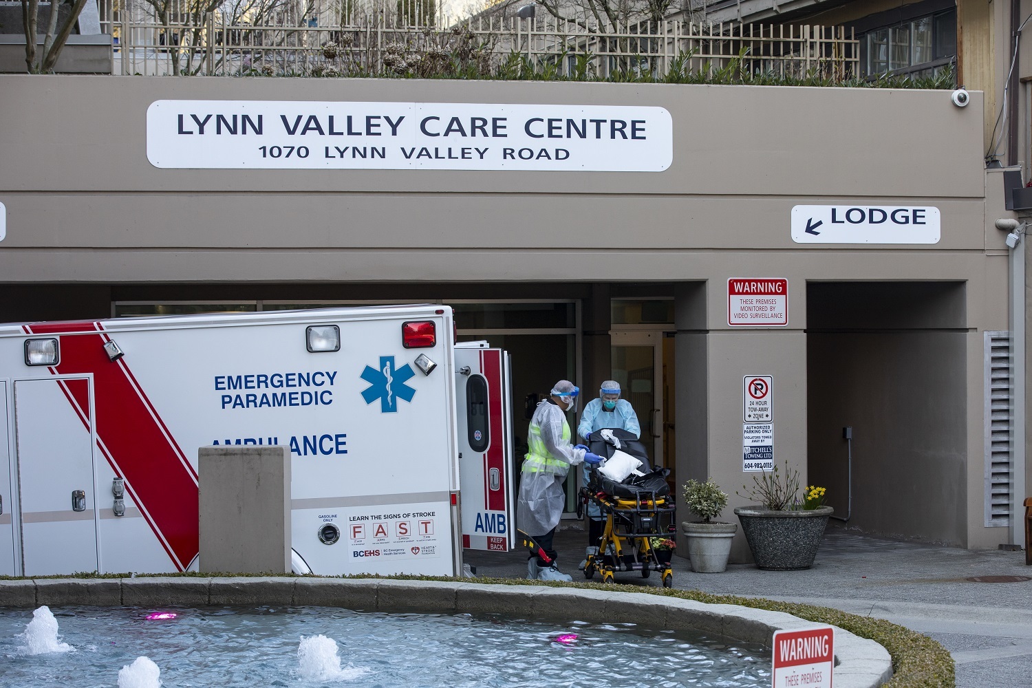 Paramedics wearing full body protective equipment clean a stretcher after responding to a call at the Lynn Valley Care Centre in North Vancouver, British Columbia on Friday, March 20, 2020. (Ben Nelms/CBC)