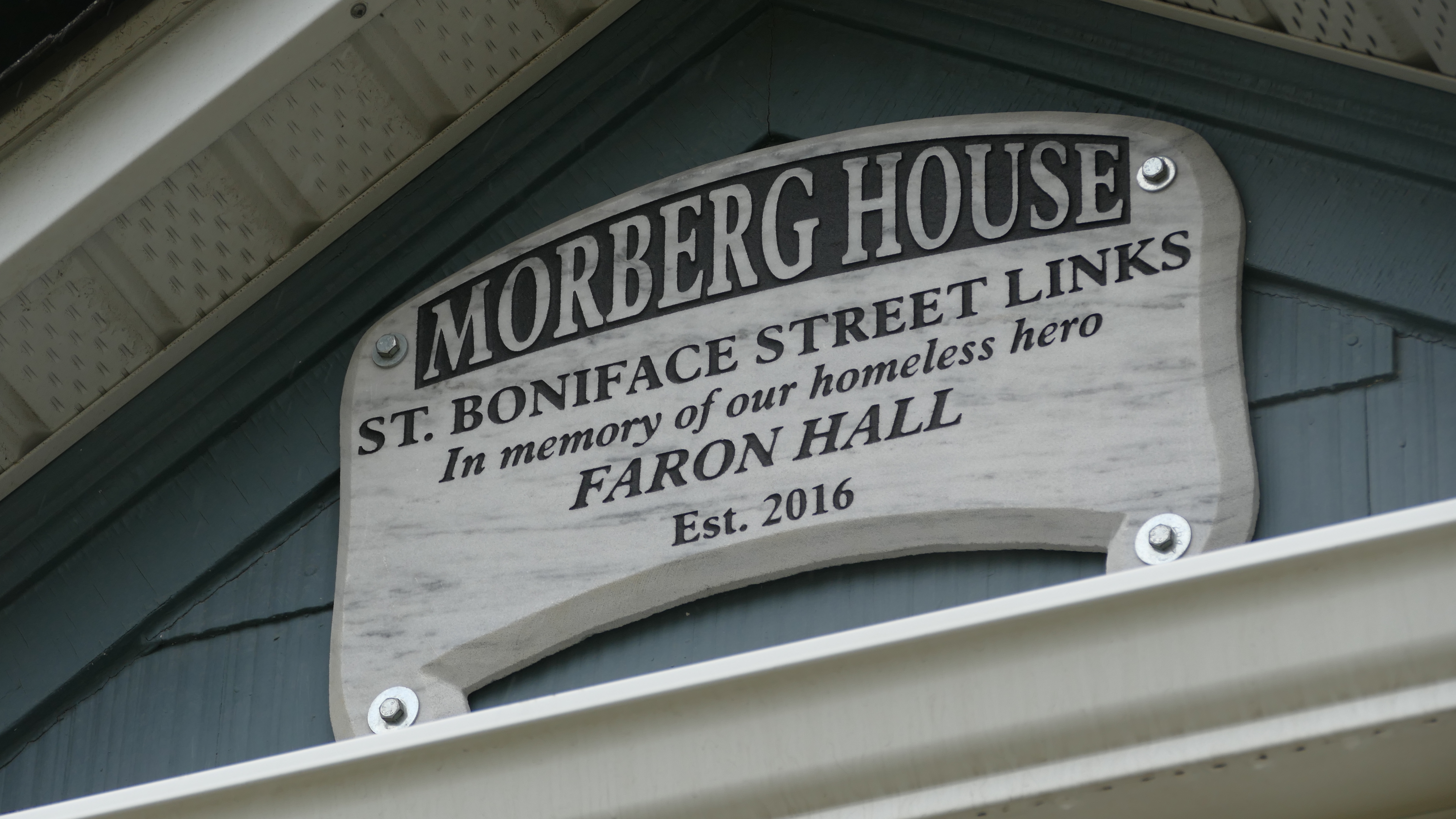 A plaque dedicated to Faron Hall, nicknamed Winnipeg's 'homeless hero' after he saved a teen from drowning in the Red River, sits above the door of Morberg House. Hall drowned in the same river in 2014. (Warren Kay/CBC)