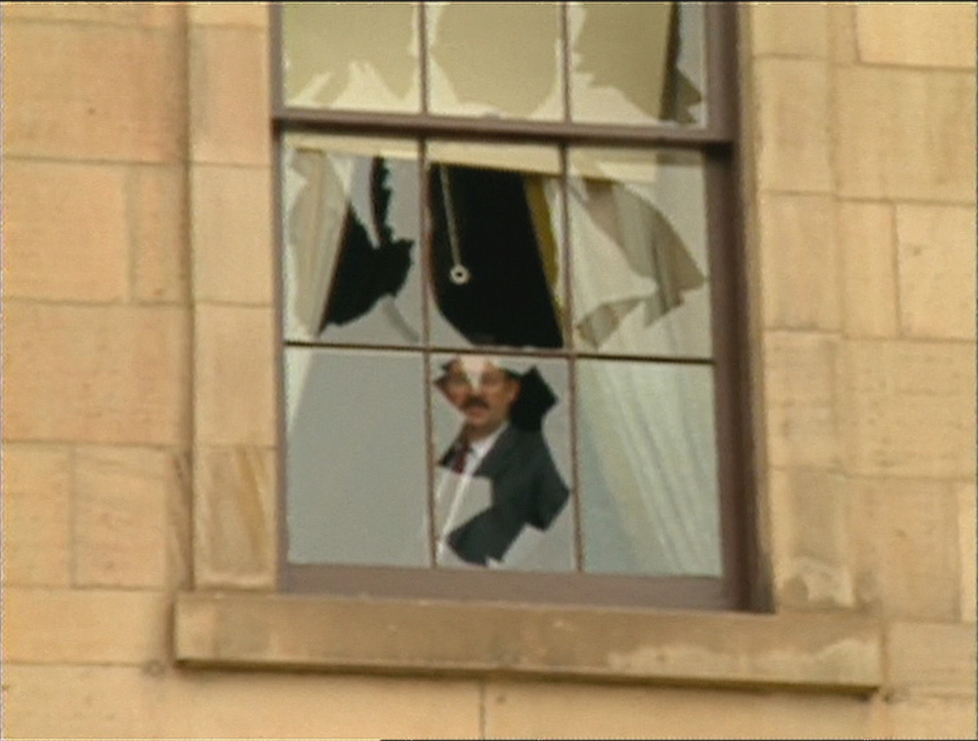 A man looks out from a shattered window at Province House. (CBC)