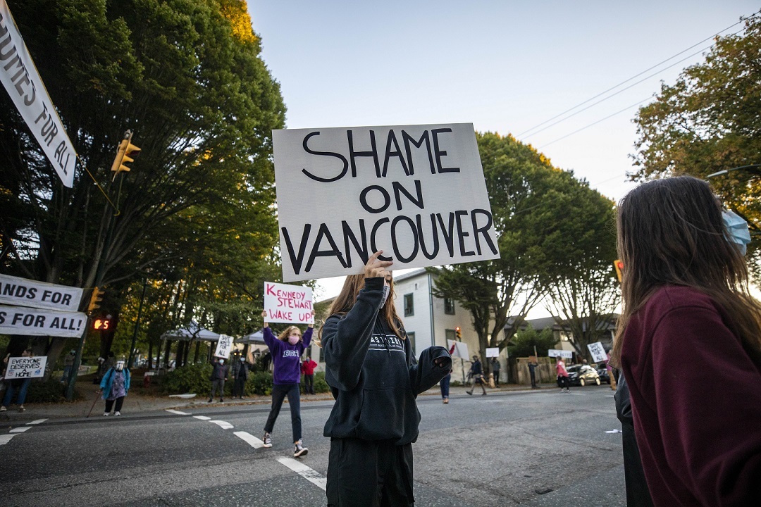 Demonstrators hold signs near Strathcona park calling for safe housing of homeless people camped in the park in Vancouver in September. Pete Fry, city councillor, says a sort of "protest leadership" at the encampment has made it challenging for outreach workers to connect with campers. (Ben Nelms)