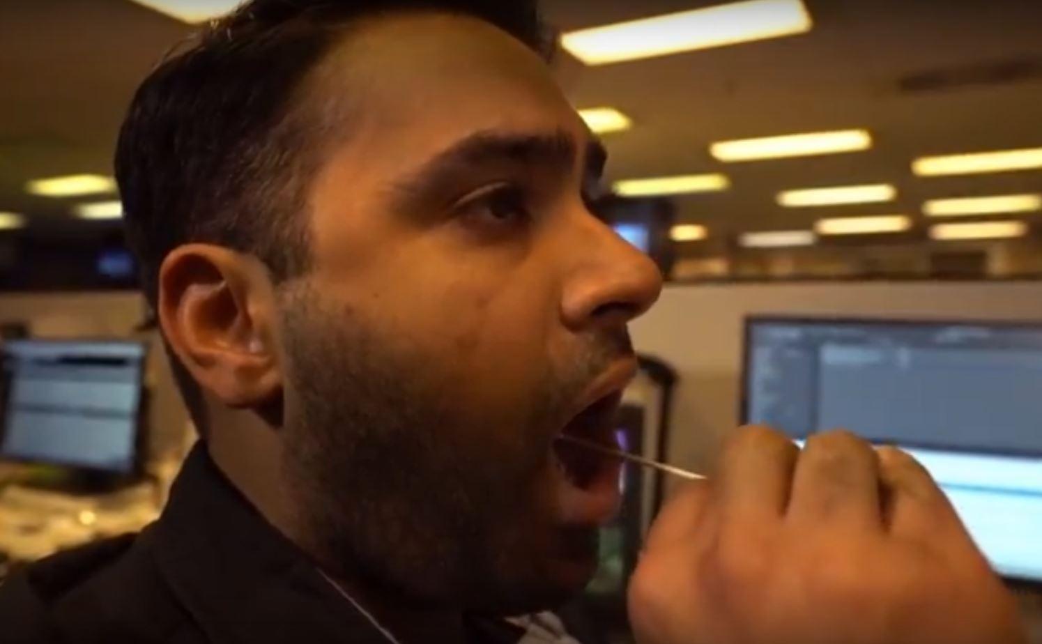 A CBC employee in Toronto swabs the inside of his cheek to obtain a DNA sample. (CBC)